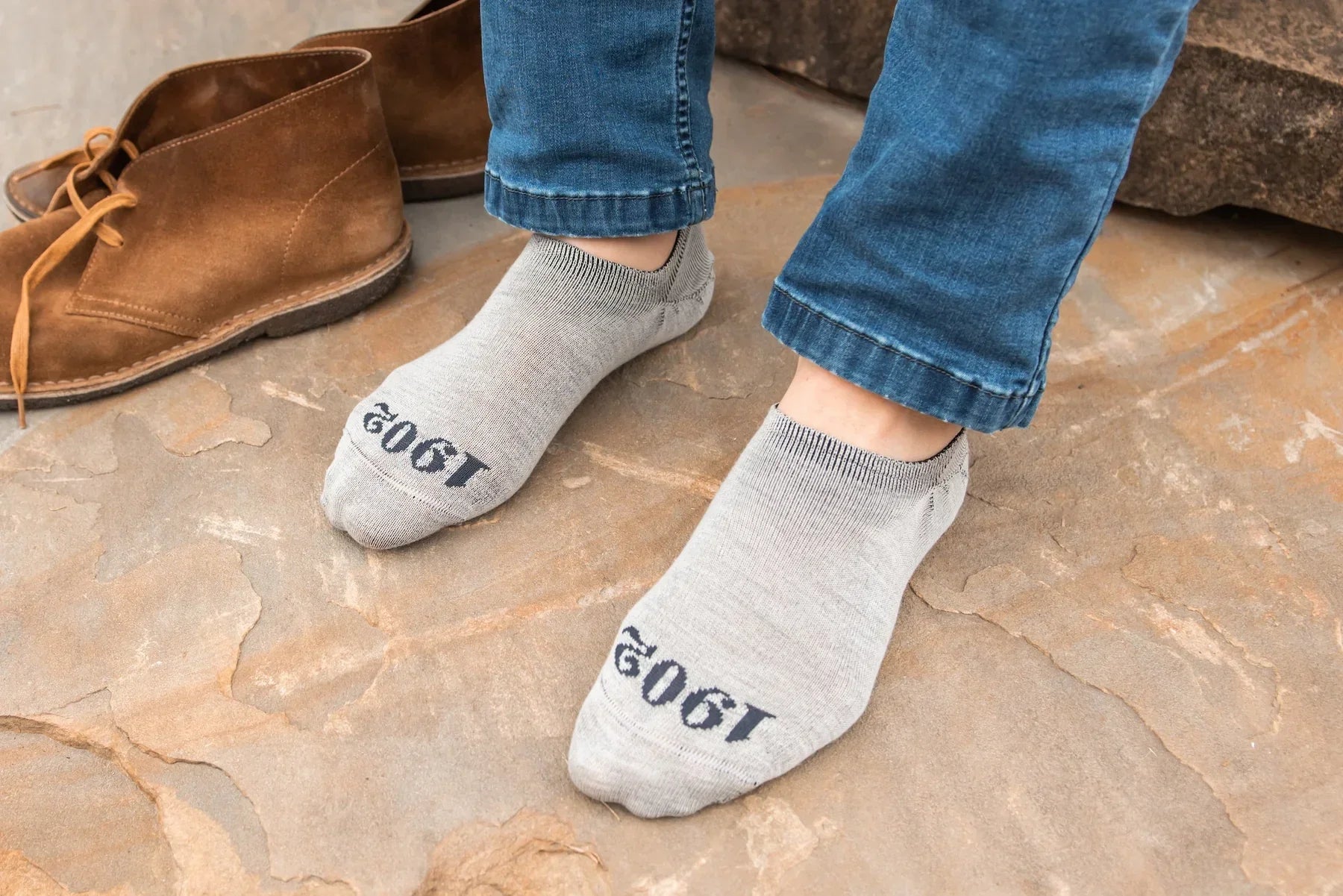 Mens socked feet next to boots on rock